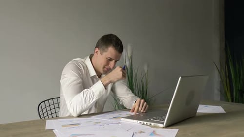businessman works with documents, schedules at the desk in front of a laptop