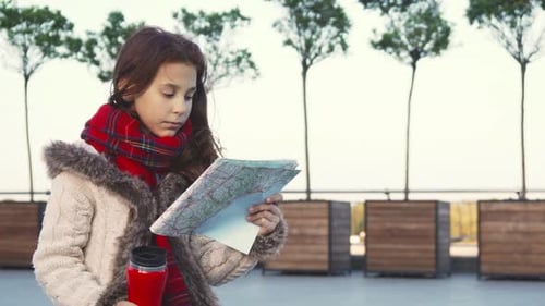 Girl with Map and Thermos Standing Outdoors