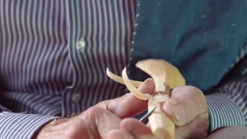 Senior Adult Carving Wood with Knife