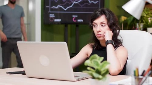 El gerente se sienta en la computadora, mira el reloj y se da cuenta de que llega tarde a una reunión