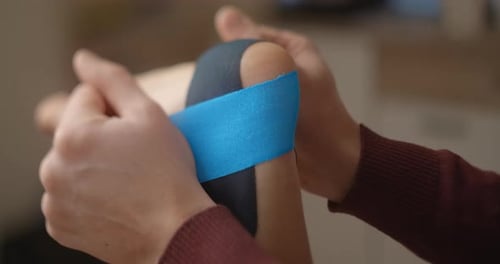 Applying a strip of therapeutic tape for sports