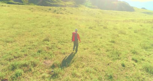 Flight Over Backpack Hiking Tourist Walking Across Green Mountain Field