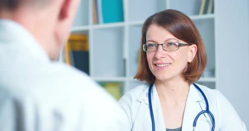 Female doctor therapist consults a male patient in the office of a medical clinic. 4K.