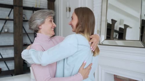 Affectionate Grandmother Hugs Her Granddaughter in Living Room