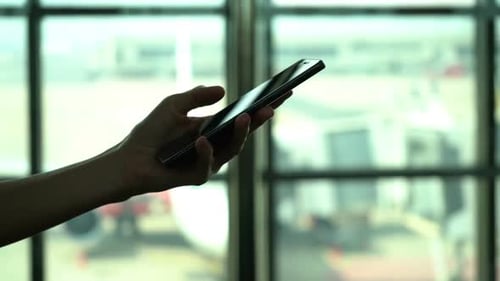 Person Using a Cell Phone in Front of Window