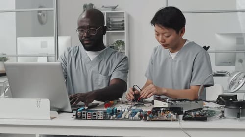 Ingenieros que utilizan multímetro y computadora portátil en laboratorio