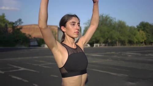 Young Woman Stretching Arms in Urban Setting
