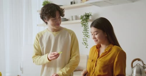Young Couple Cooking Together at Home, Eating Vegetables