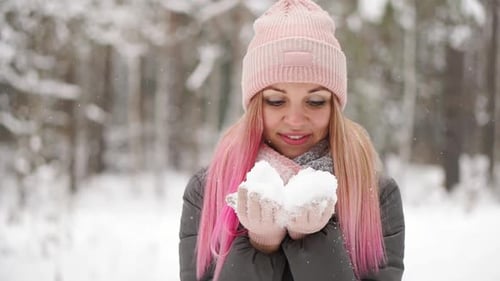 Slow Motion, a Woman in a Jacket Hat and Scarf in the Winter in the Forest Holding Snow in Her Hands