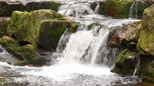 Scenic Waterfall Cascading Over Moss Covered Rocks