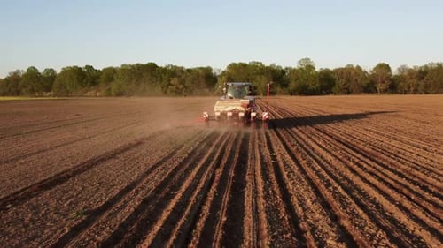 Tractor Working in Field at Sunset