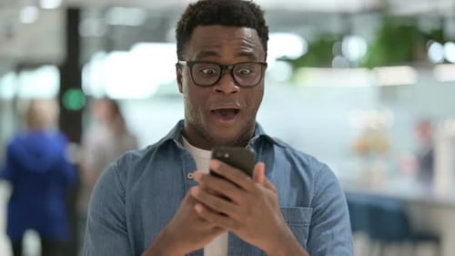 Young Adult Cheers While Looking At Phone