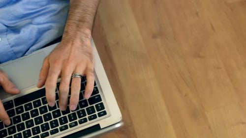 Adult Typing on Laptop on Wood Floor