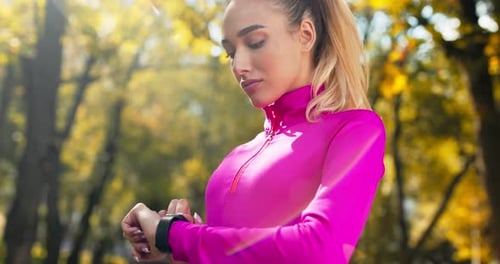 Millennial Blonde Turning on Training Mode on Smartwatch, Preparing for Run Workout in Autumn Park