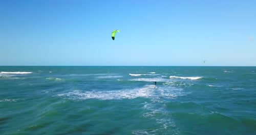 Aerial drone view of a man kiteboarding on a kite board.