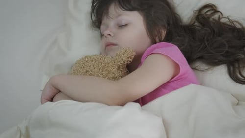 Sleeping Child Hugging Teddy Bear in Bed