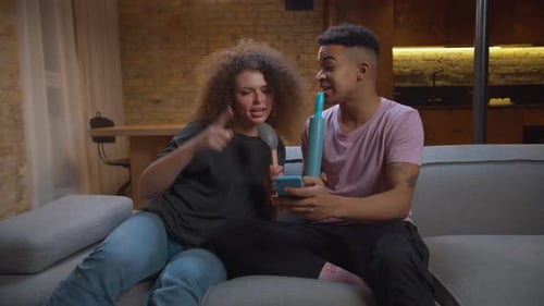 Friends Singing Karaoke Together at Home on Couch