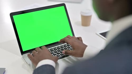 Vista trasera de un empresario africano usando una computadora portátil con pantalla Chroma Key