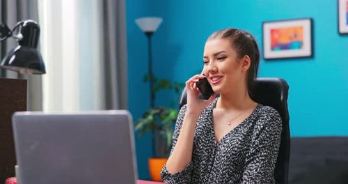 Smiling Woman Talking on Phone at Desk