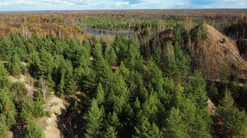 Flying above the abandoned quarry with forest and lake in autumn