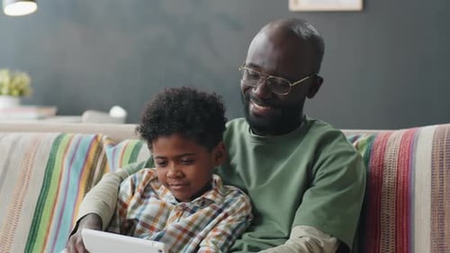 Father and Son Looking at Tablet on Couch