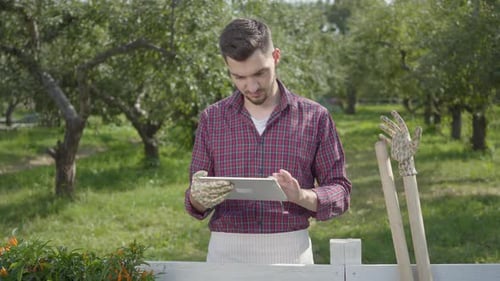 Young Adult Using Tablet in Rural Orchard