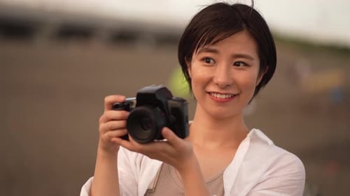 Smiling Woman Taking Pictures with Camera Outdoors