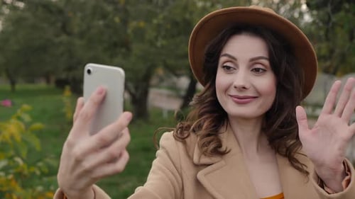 Woman Waving on Phone in Park