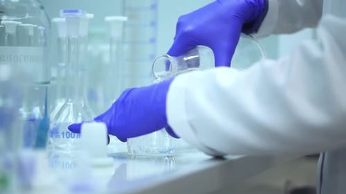Gloved Hands Pour Liquid in Laboratory Experiment
