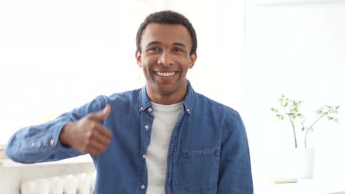 Smiling Man Gives Thumbs Up Gesture Indoors