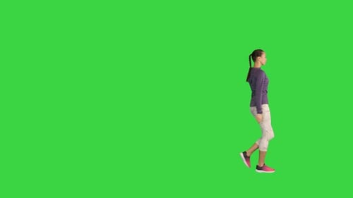 Young Woman Using Her Smart Watch While Walking on a Green Screen Chroma Key