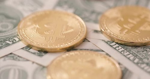 Gold Bitcoins on US Dollar Bills Close Up