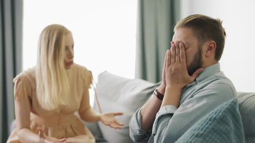 Blonde Woman Arguing with Man on Gray Couch