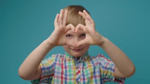Happy Child Making Heart Shape with Hands