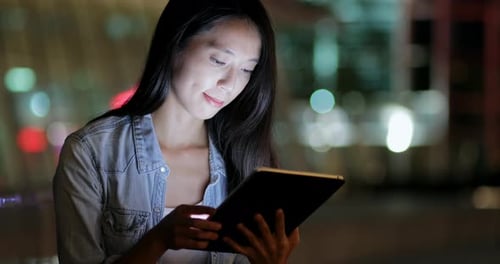 Woman Using Tablet Device at Night in City