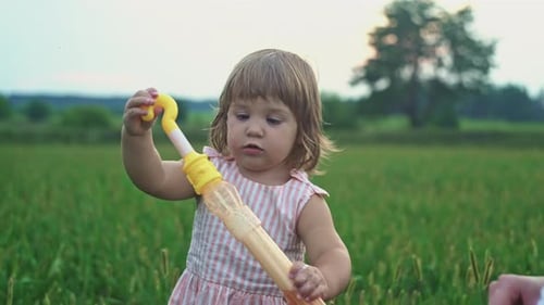 A Little Girl Tries to Blow Soap Bubbles in Nature