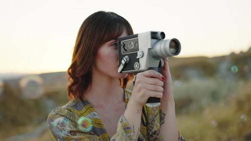 Young Woman Filming with Vintage Camera Outdoors