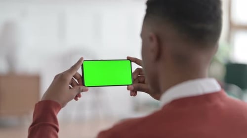 Rear View of African Man Looking at Smartphone with Green Chroma Screen