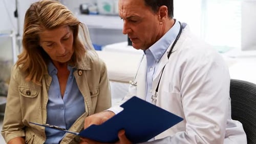 Doctor Reviews Chart with Patient in Examination Room