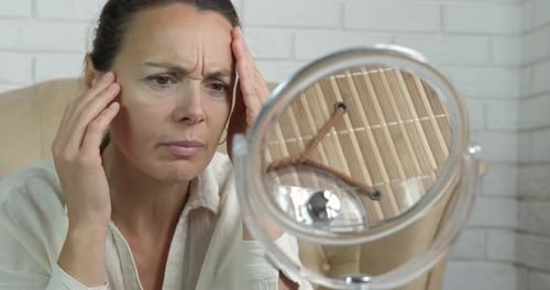 Woman Examining Her Face in a Mirror