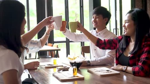 Young Business People Raising Cup of Coffee Together and Say Cheers on the Table at the Cafe