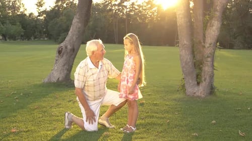 Grandfather Talking with Granddaughter in Park.
