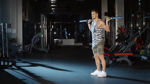 Athletic Sportsman trainiert seine Beine mit Langhantelgewicht im Fitnessstudio
