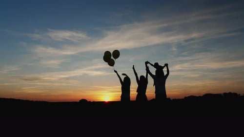 Silhouette Family with Balloons at Colorful Sunset