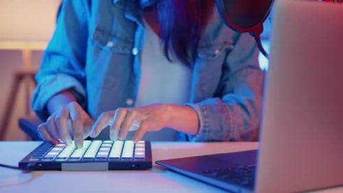 asia girl dj use launchpad synthesizer keyboard sound mixer wear headphone made music in laptop.