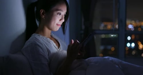 Woman watching on digital tablet at night
