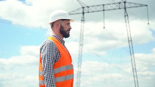 Construction Worker Standing near Electrical Tower
