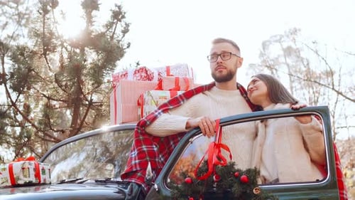 Loving Couple With Christmas Gifts Next to Car
