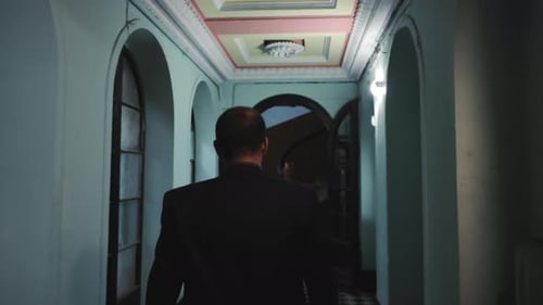 Man in Suit Walking Through Lit Hallway