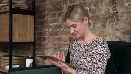 Woman Uses Tablet on Couch in Urban Interior